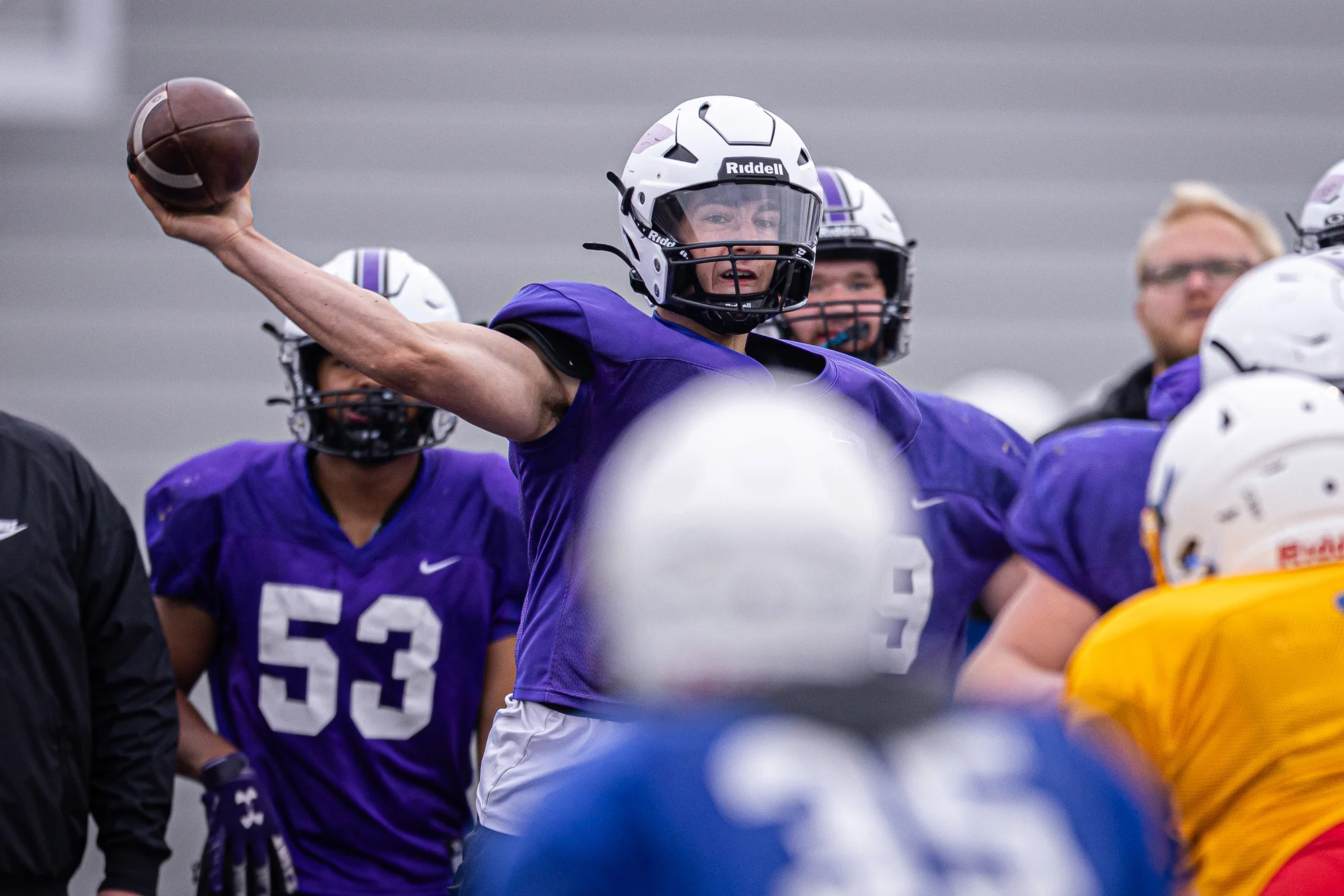QB throwing the ball as his teammates look on